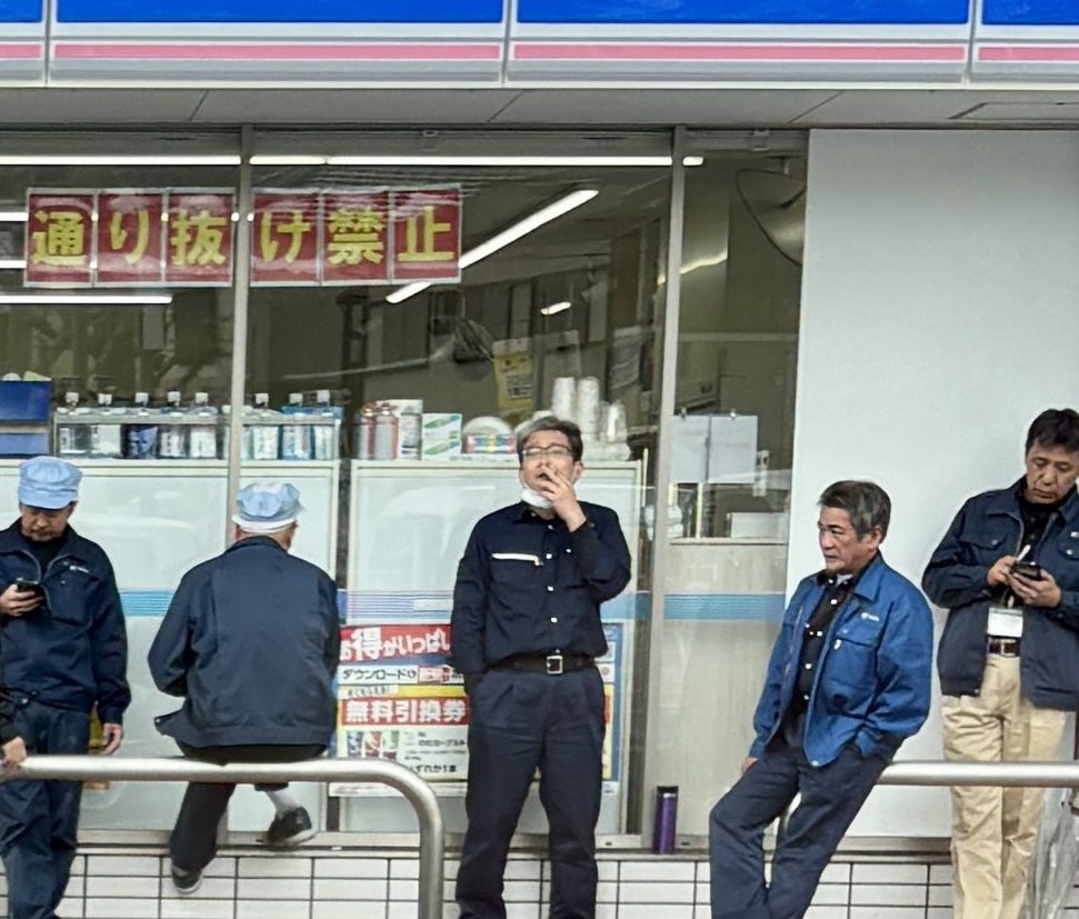 Lawson convenience store workers in Japan taking a smoke and phone break outside the storefront