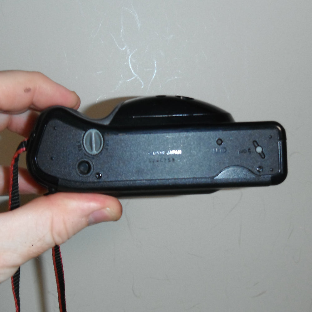Camera resting on neutral background with wrist strap attached